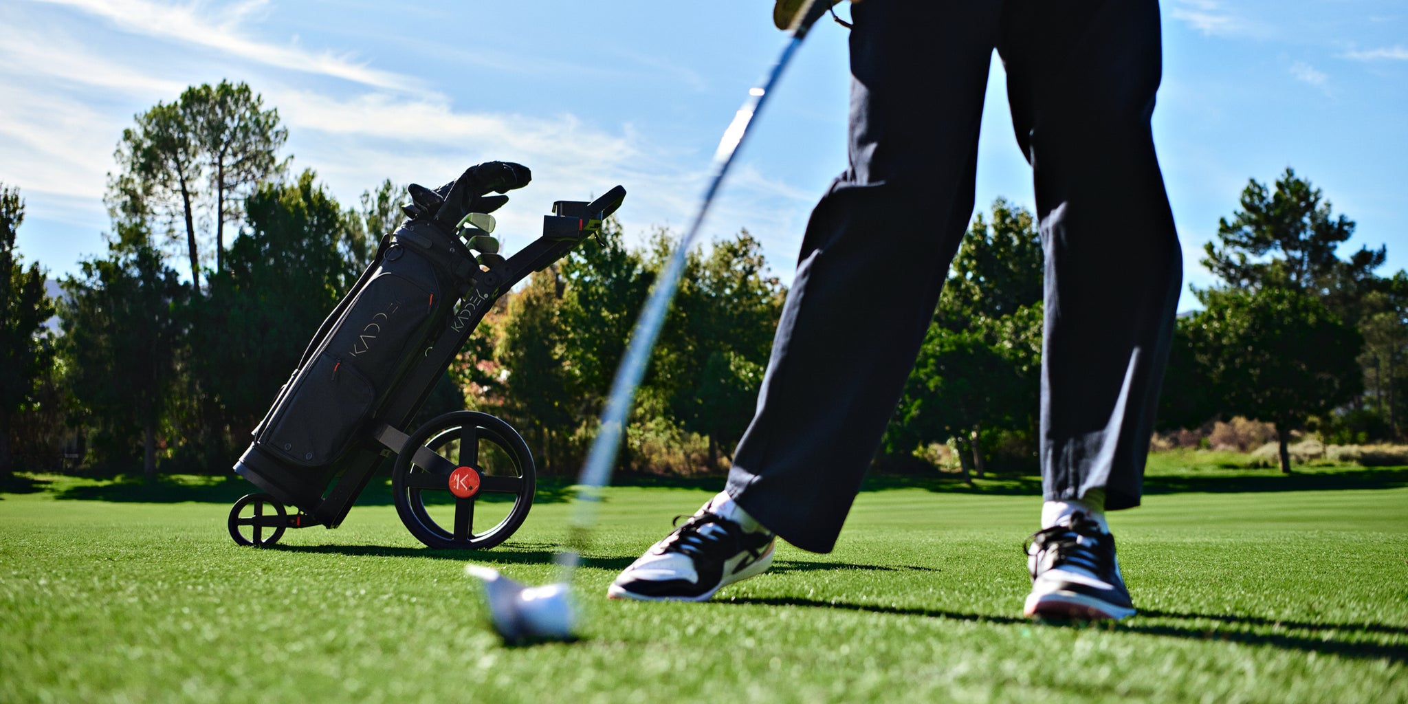 Kaddey golf trolley and bag set up on a fairway beside a golfer