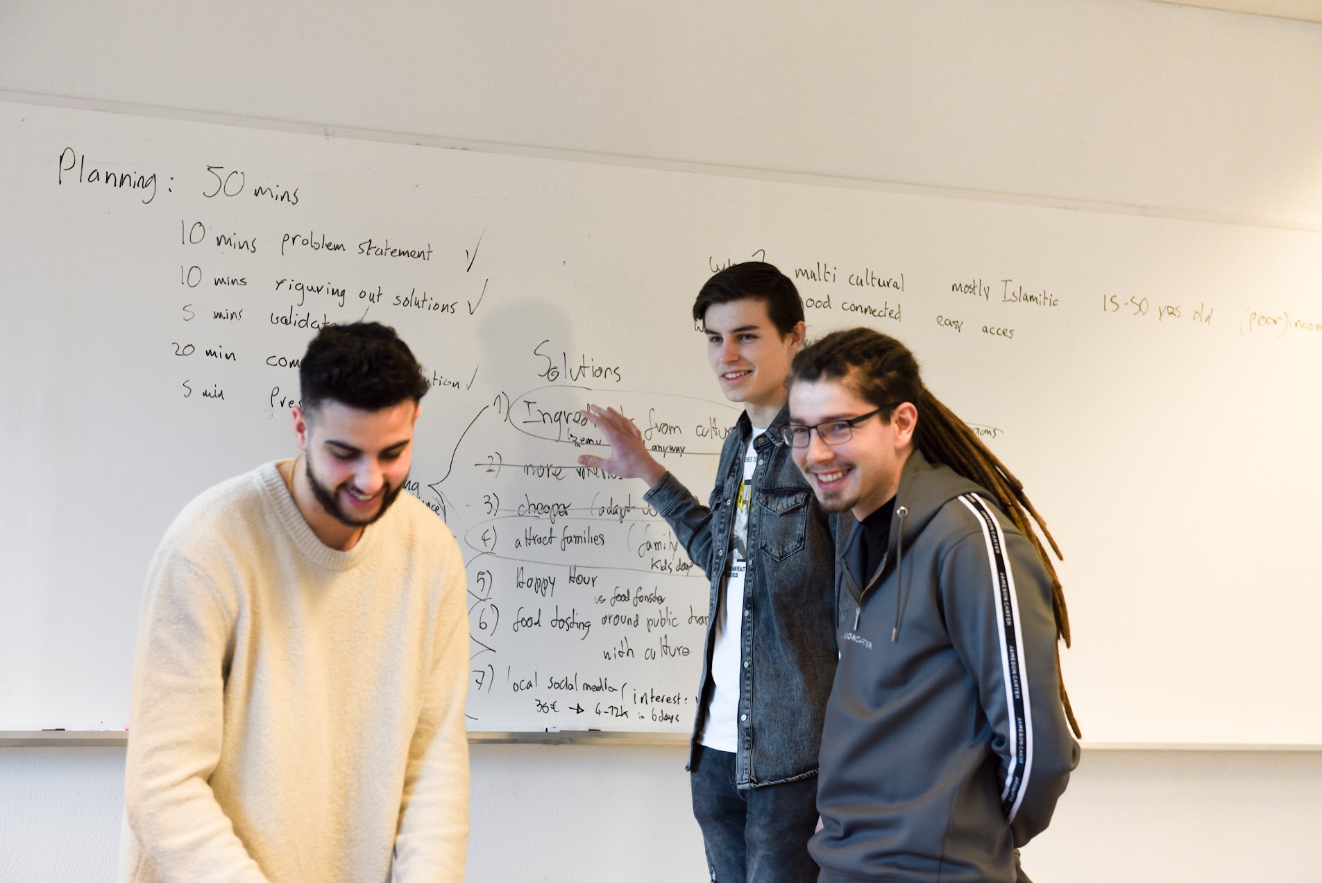 A team laughing together in front of a whiteboard full of plans